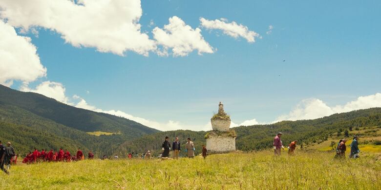 Still frame from the film The Monk and the Gun. Wide shot of people gathered in a field in Bhutan.