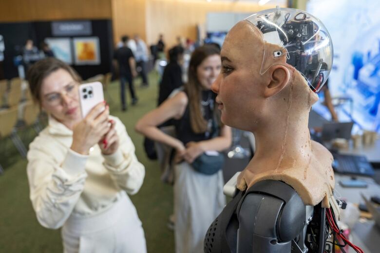 A woman takes a picture of a humanoid robot with a transparent skull. 