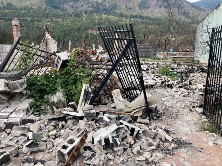 An iron fence leans haphazardly amid a pile of rubble.