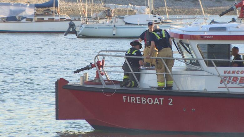 A red boat in water with fire fighters on board