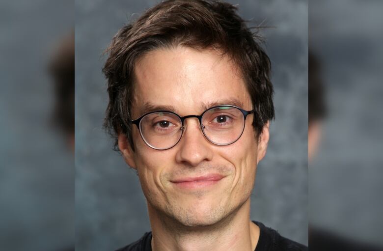 Closeup of a smiliing man with dark hair and glasses. 