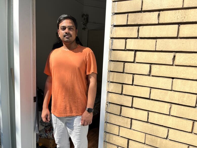 A man stands in a doorway of his apartment.