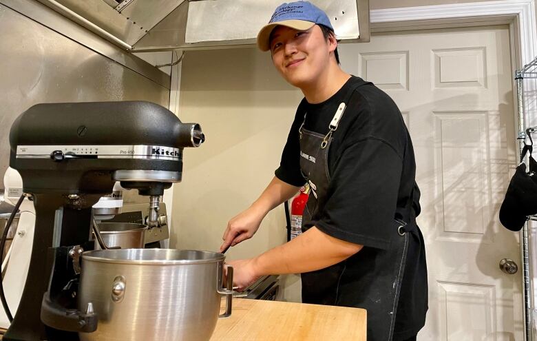 A baker inside a kitchen leaning over a cooker.