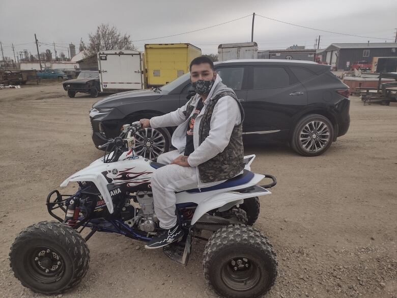 A young man wearing a mask on a 4-wheeler.