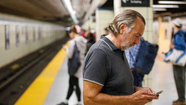 Commuters are photographed on their phones at Yonge Station in Toronto, on Aug. 23, 2023.