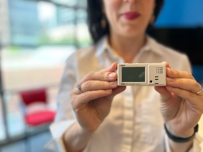 A woman holds a temperature and humidity sensor.