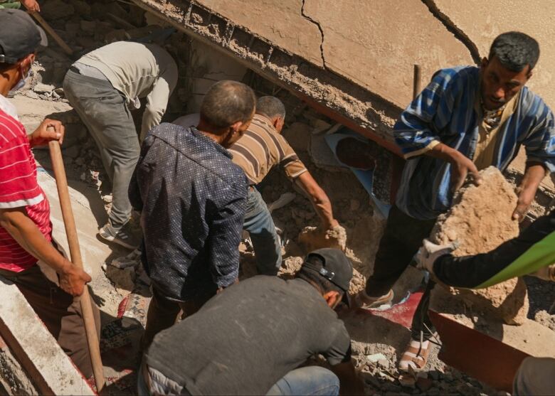 Villagers in Imin Tala use their bare hands to dig out debris from the community's mosque.  They believe the local imam may still be alive undernearth.