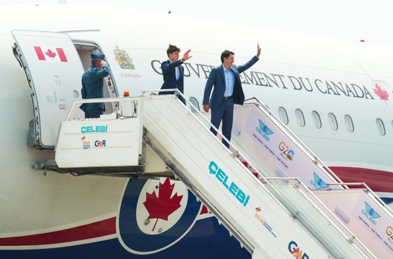 Prime Minister Justin Trudeau waves as he boards an airplane along with his son.