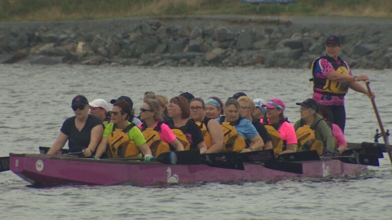 Women with life jackets in a long purple boat paddle