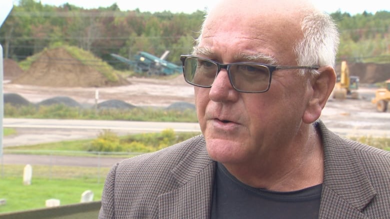 Daniel Legere stands outside wearing glasses and a blazer.