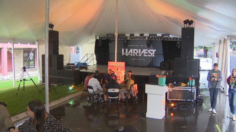 People sit and stand inside a large tent.