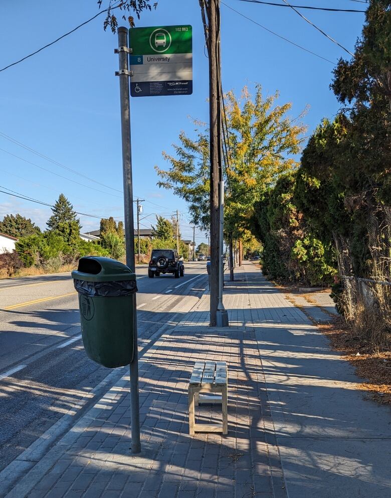 A bus stop with a small wooden bench. 