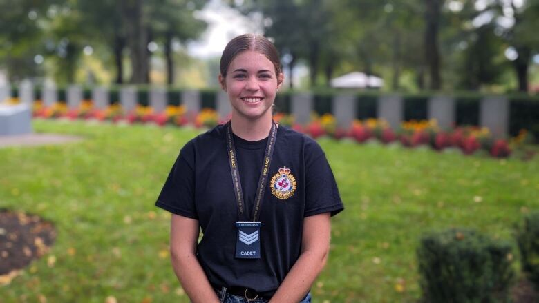 A cadet stands in front of a row of gravestones