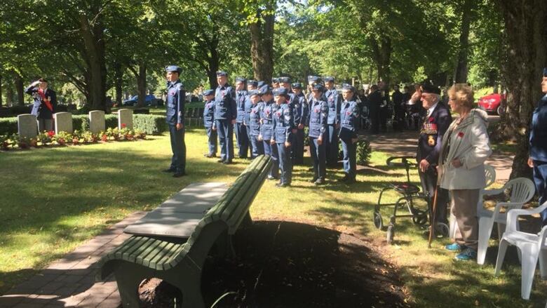 Cadets standing at attention at a ceremony in a cemetery 