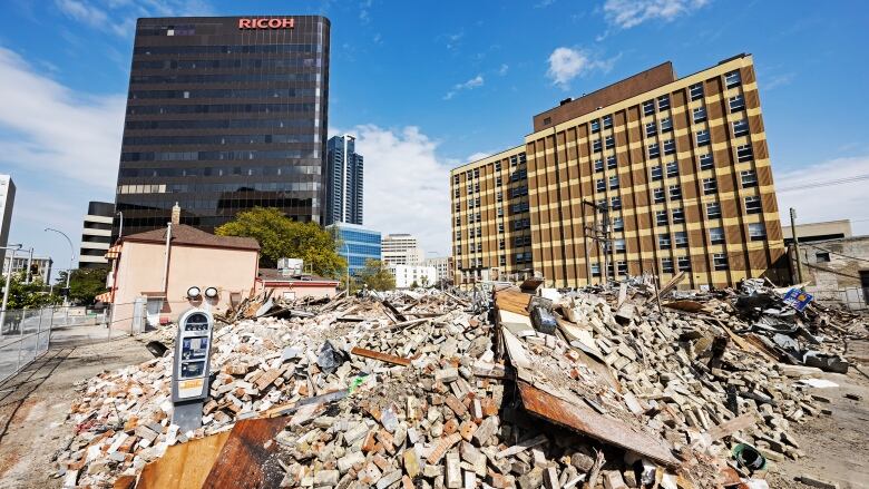 A pile of debris sits in front of tall buildings.