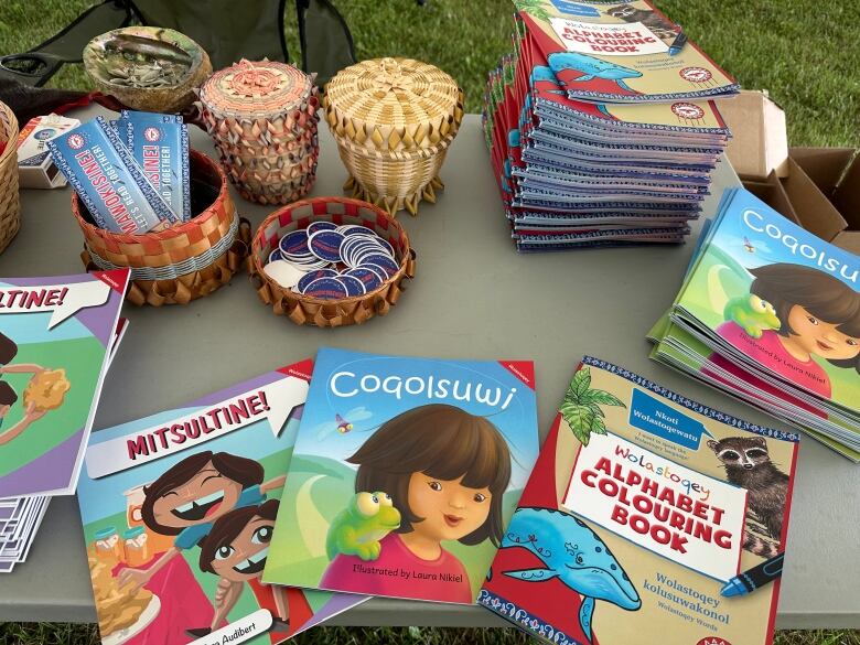 Children's colouring books are spread out across a grey folding table.