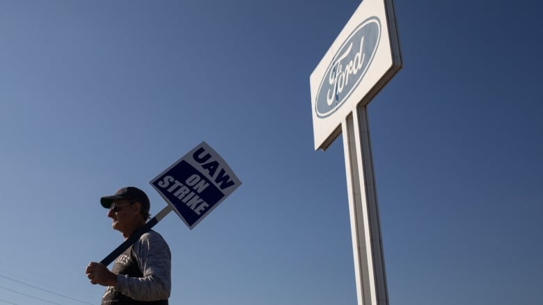 A striking UAW worker holds a sign outside a Ford facility in Wayne, Michigan.