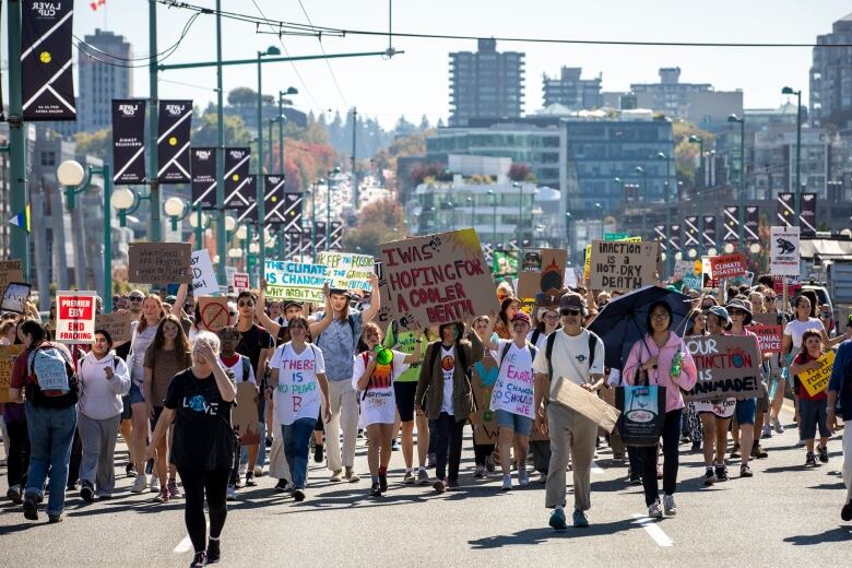 A line of people are walking forward with signs raised above their heads. 