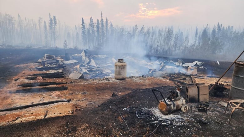 The burned remains of a house are seen still smouldering.