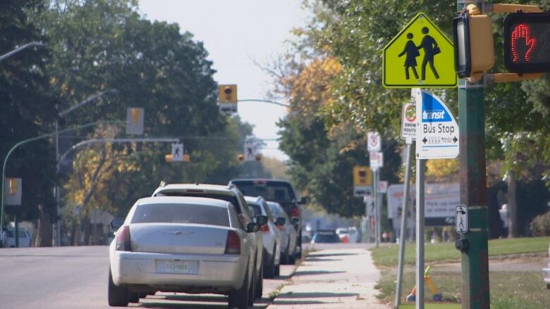 A city street with a school zone side beside a bus stop