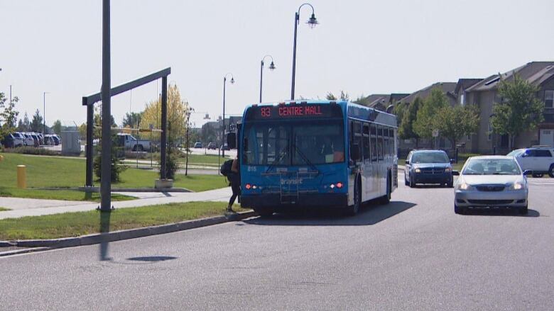 A city transit bus picks up a passenger