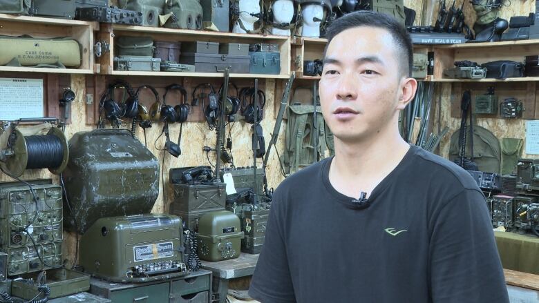 A person is interviewed in front of military equipment.