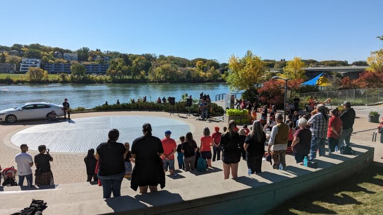 Dozens stand at River Landing, many wearing shirts with the faces of Megan Gallagher or that make reference to Missing and Murdered Indigenous Women.