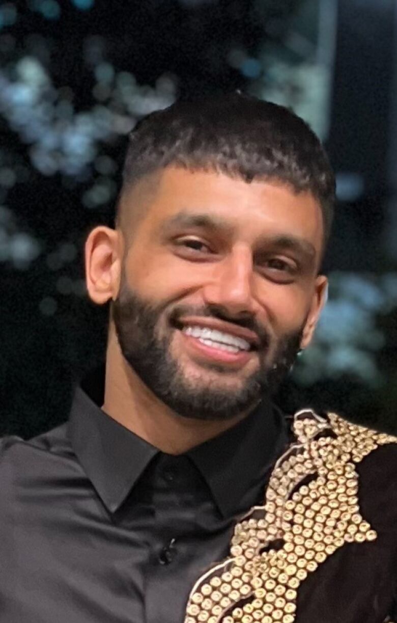 A young South Asian man with a beard smiles at the camera.