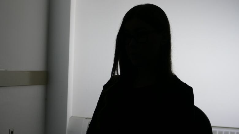 A woman appears in silhouette to conceal her identity. 