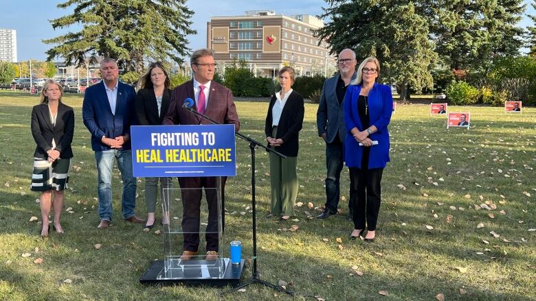 People standing in a park behind a podium.