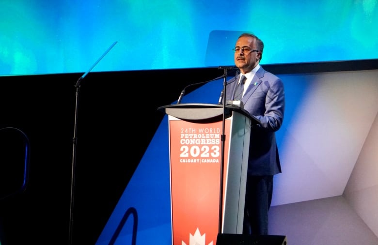 An oilpatch executive speaks at a podium on a conference stage.