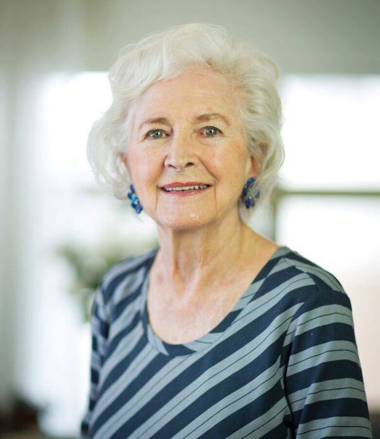 A woman wearing a striped shirt inside a bright room. 