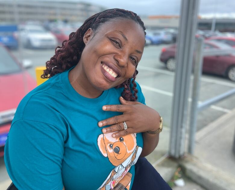 A woman sits in a bus shelter. She's smiling.