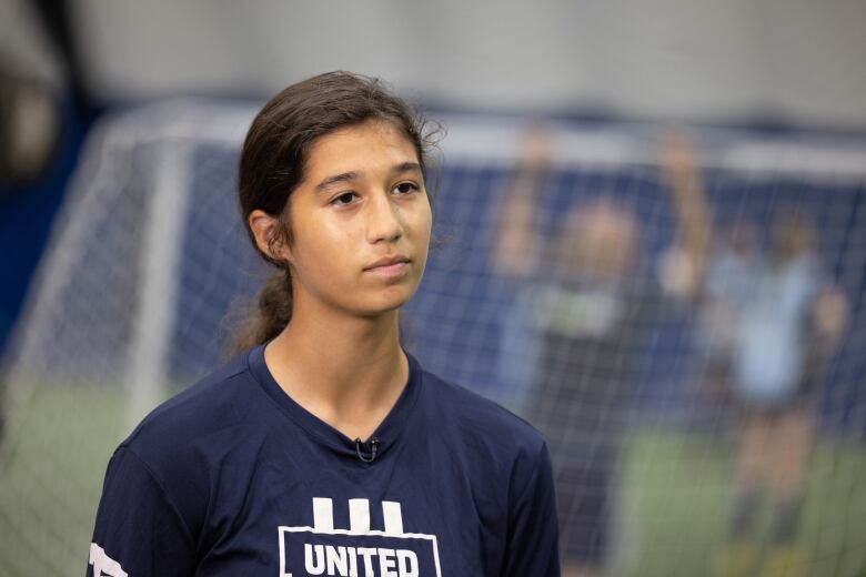 A teenage female soccer player is shown wearing a blue uniform with white writing that says United.