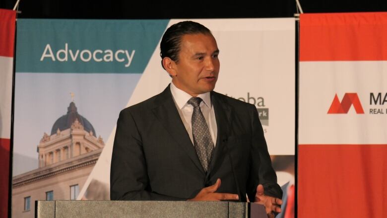 A man in a suit gesticulating behind a podium.