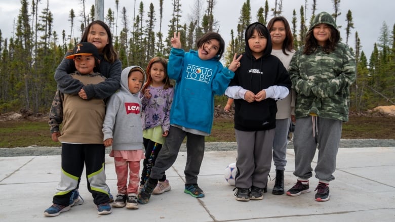 A group of students pose for a group photo on an outdoor basketball court.