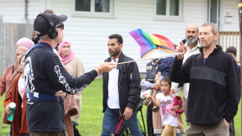 Man holds pride flag while another man points his finger at him