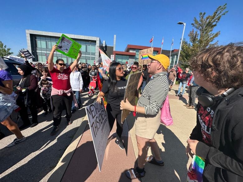 Two people speak in close quarters while holding signs.