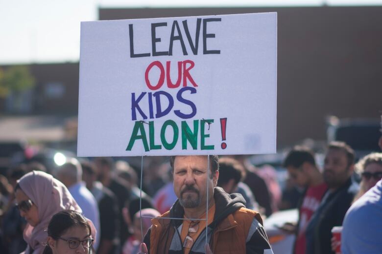 A man standing, holding a sign.