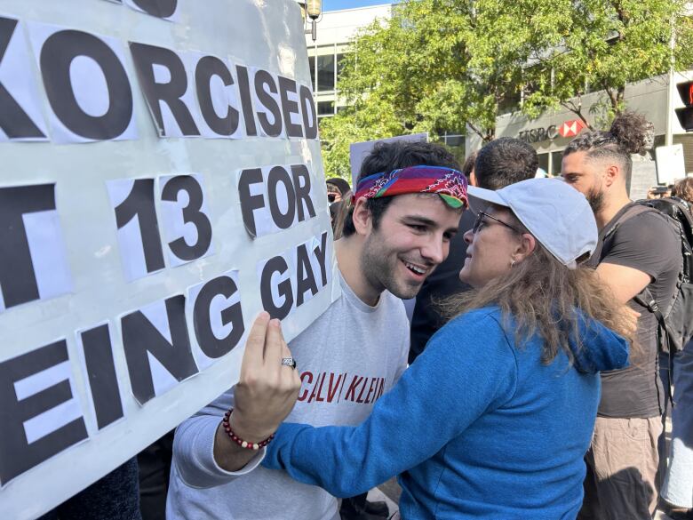 A woman is about to hug a protester holding a sign. 