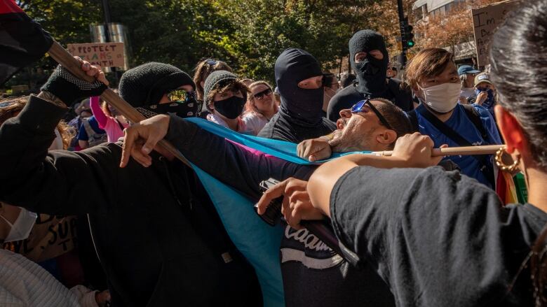 A man appears to be caught between two people who are shoving him