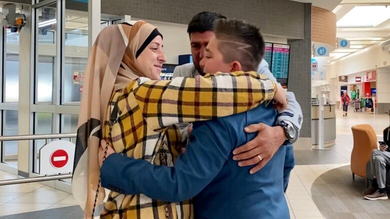 Parents hug son at airport.