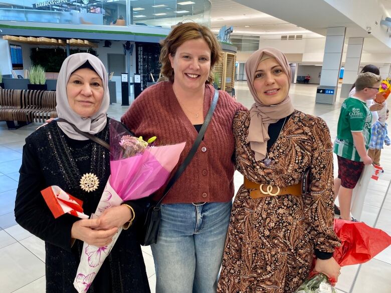 Three women stand together at the aiport. 