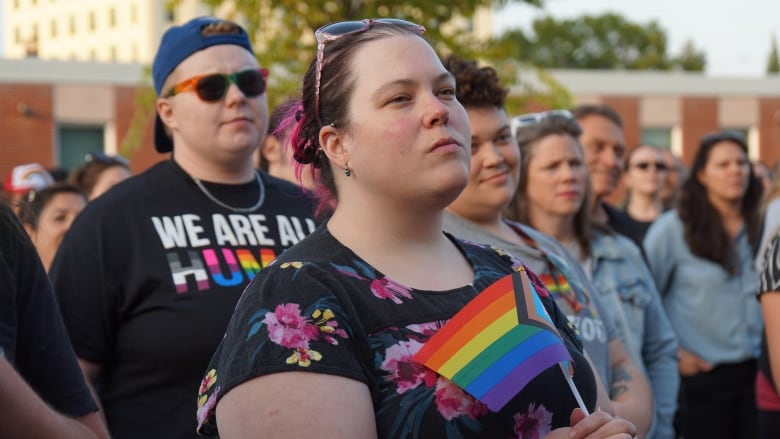 People in a crowd hold rainbow-coloured pride flags.