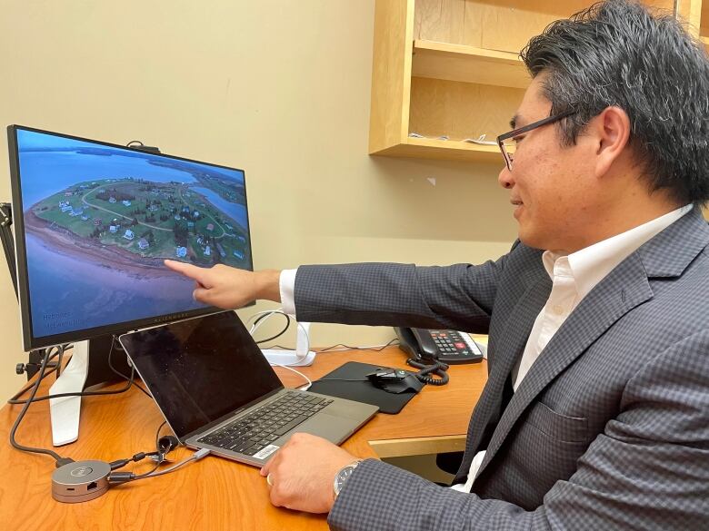 Xander Wang sits in his office, with his computer in front of him.  He points to a screen shot of drone footage gathered by his colleagues after post-tropical storm Fiona. 