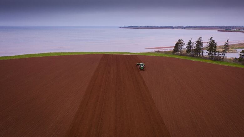 Drone shot of planting barley in a huge red field near the Northumberland Strait in Tryon PEI, taken 19 May 2021.