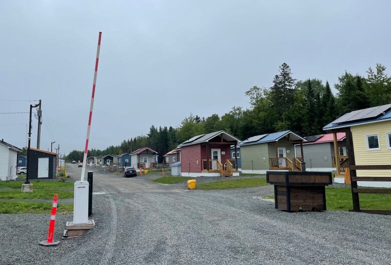 An open security gate with tiny homes behind it