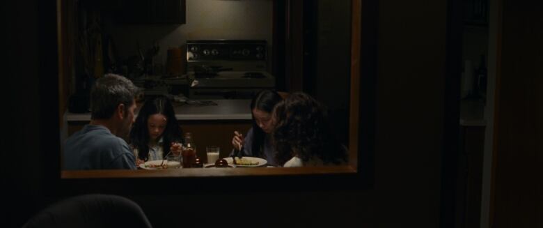 A family sits at the dinner table in dark lighting