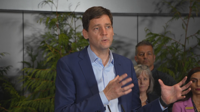 A man gestures with his hands standing at a podium.