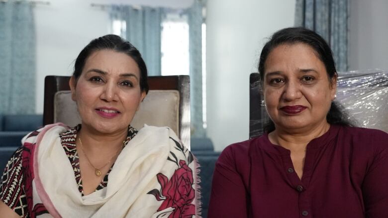 Two women pose for a photo while seated in chairs.